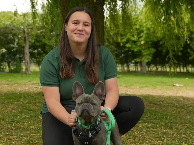 Intake and assessment officer Rochelle kneeling and smiling at camera while holding French bulldog